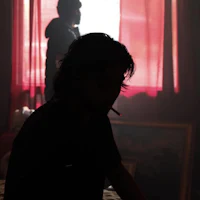 a man smoking a cigarette in front of a window