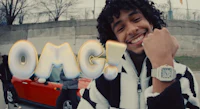 a young man with curly hair standing in front of a car with the word omg