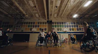 a group of people in wheelchairs playing basketball in a gym