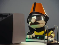 a stuffed animal wearing a hat and glasses is working on a computer