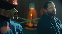 two men standing next to each other in a dark room