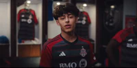 a young man in a soccer uniform standing in a locker