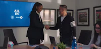 two people shaking hands in front of a tv