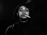 a black and white photo of a man smoking a cigarette