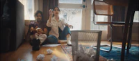 a man and woman sitting on the floor in front of a pile of papers