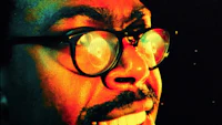 a man with glasses is smiling in front of a colorful background