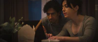 a man and woman sitting at a table looking at a laptop