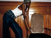 a woman is leaning against a wooden chair