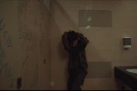 a man leaning against a wall in a bathroom