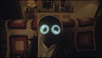 a person wearing a mask with glowing eyes sitting on a couch